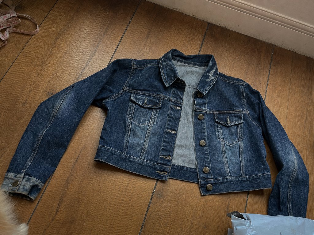 Vintage Y2K cropped denim jacket flat-lay on hardwood floor